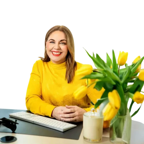 Donna Benjamin seated at desk with wase of yellow tulips